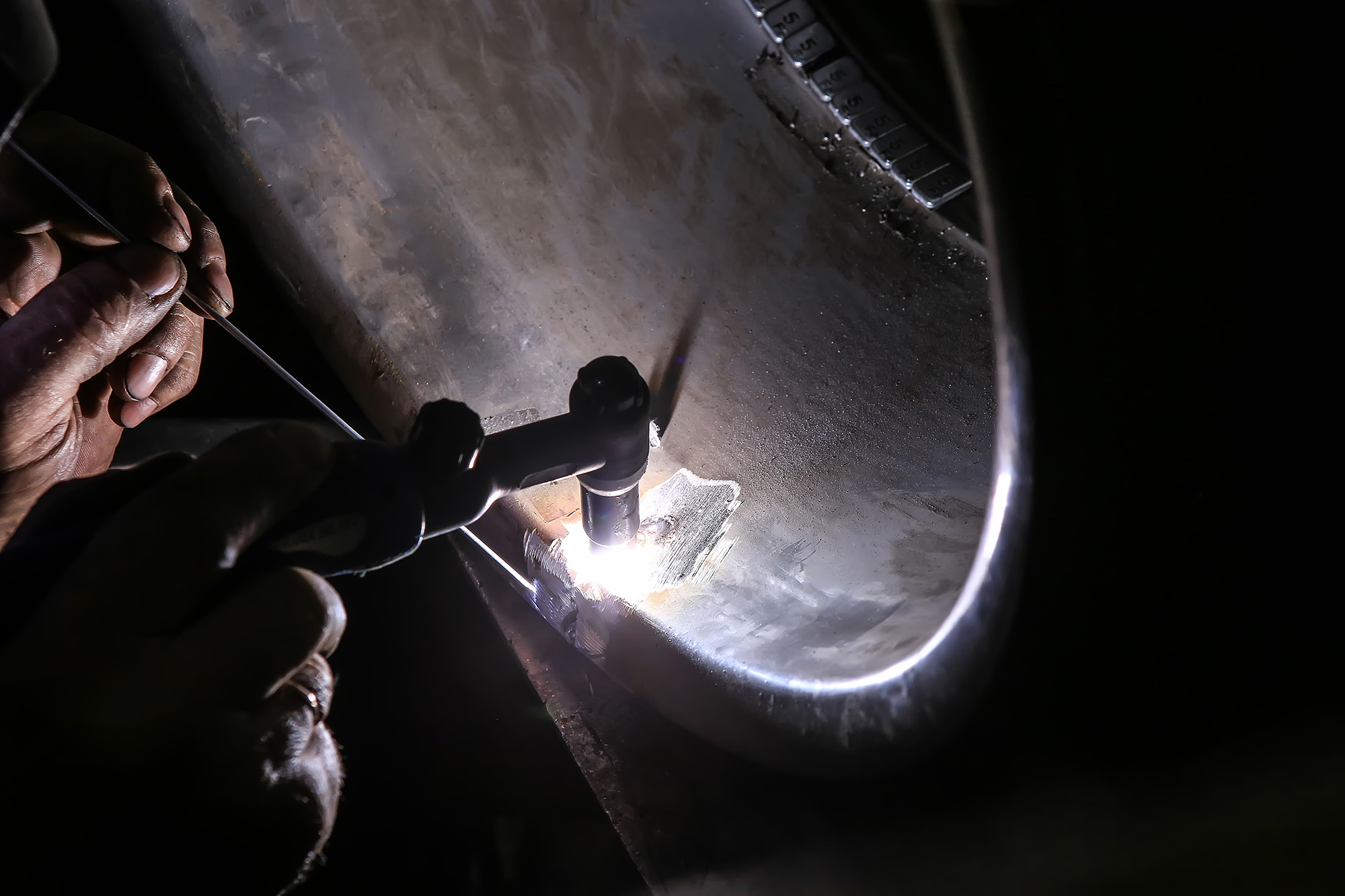 welder repairs aluminum car wheel weld